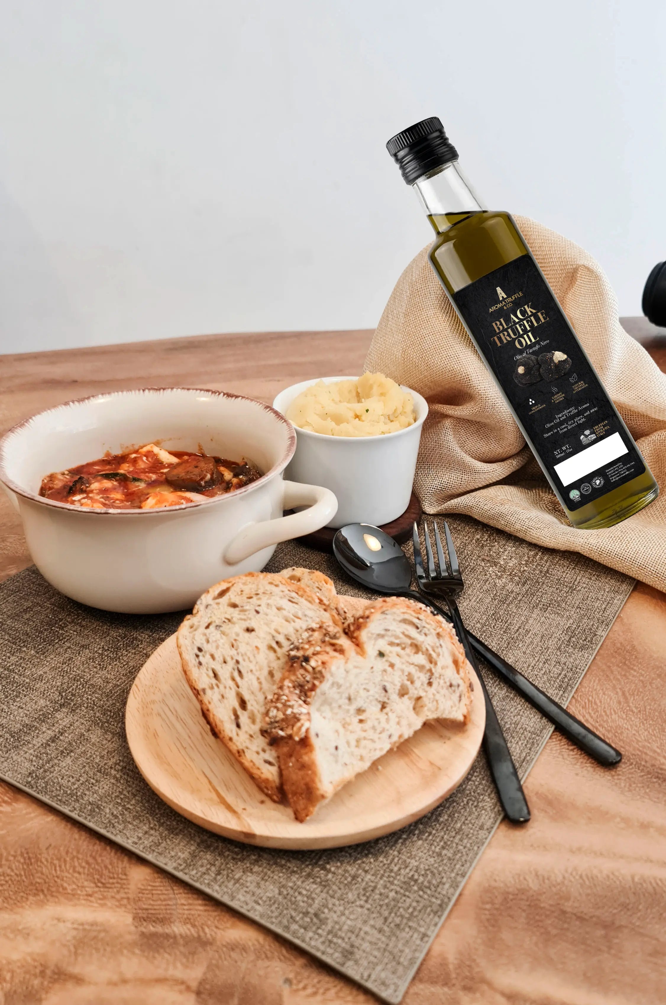Bowl of soup, bread, and Black Truffle Oil bottle on a wooden table